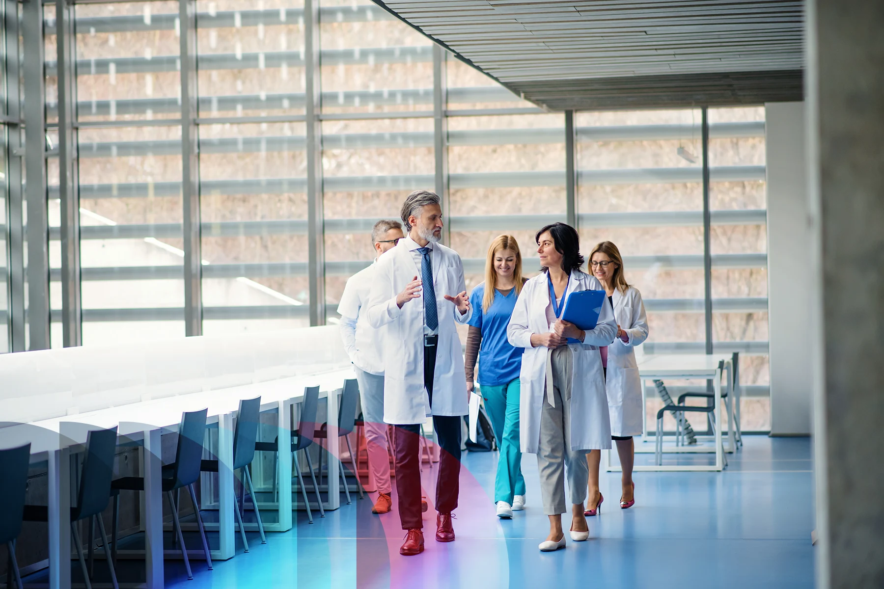 A group of healthcare professionals walk together and talk in a hospital corridor.