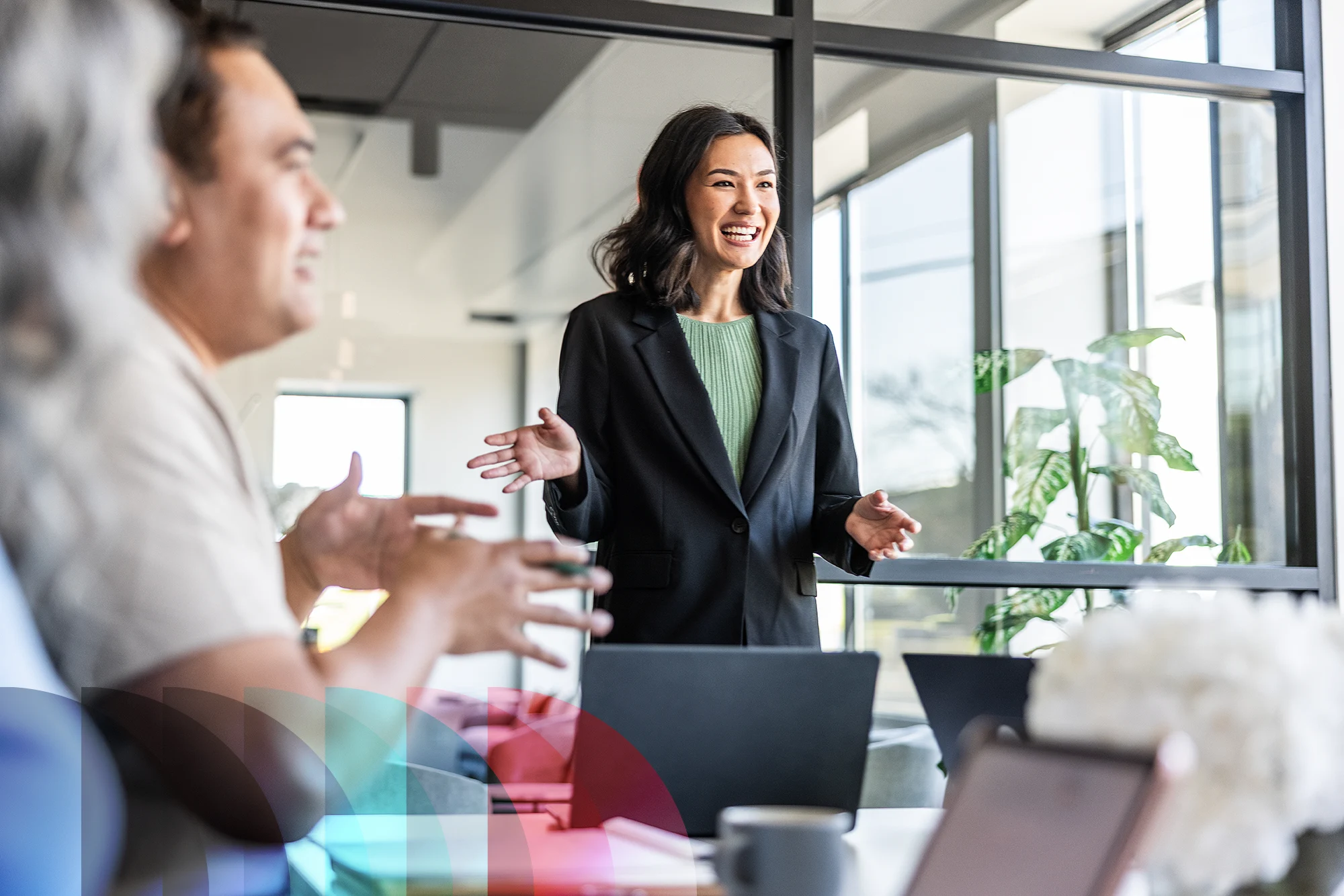 Young businesswoman speaking to colleagues in modern conference room