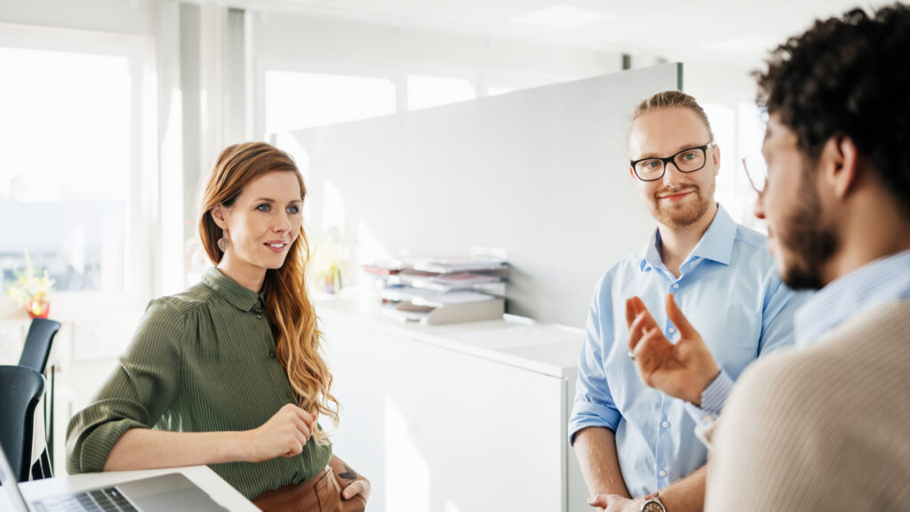 A group of employees talking to their manager about different aspects of their work at their office.