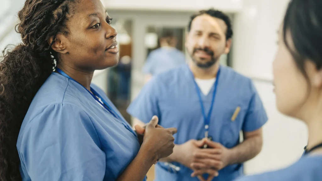 Female nurse communicating with coworker in meeting at hospital